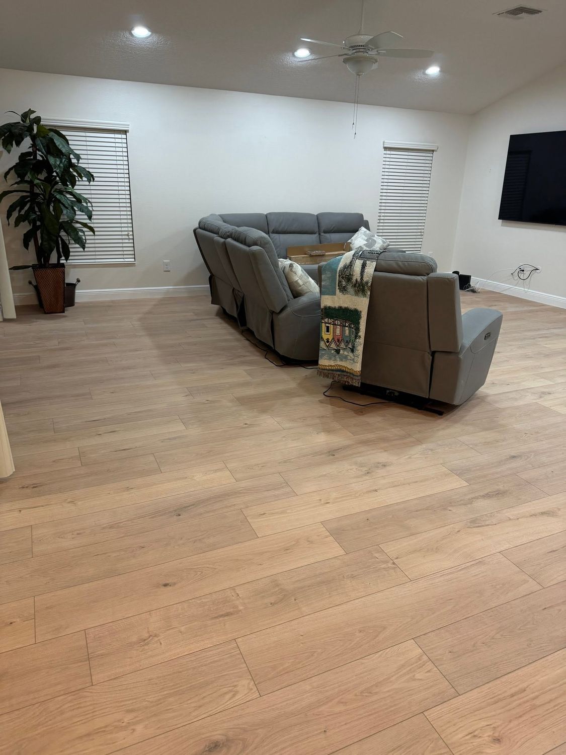 The same living room finished with wide-plank luxury vinyl flooring installed wall to wall