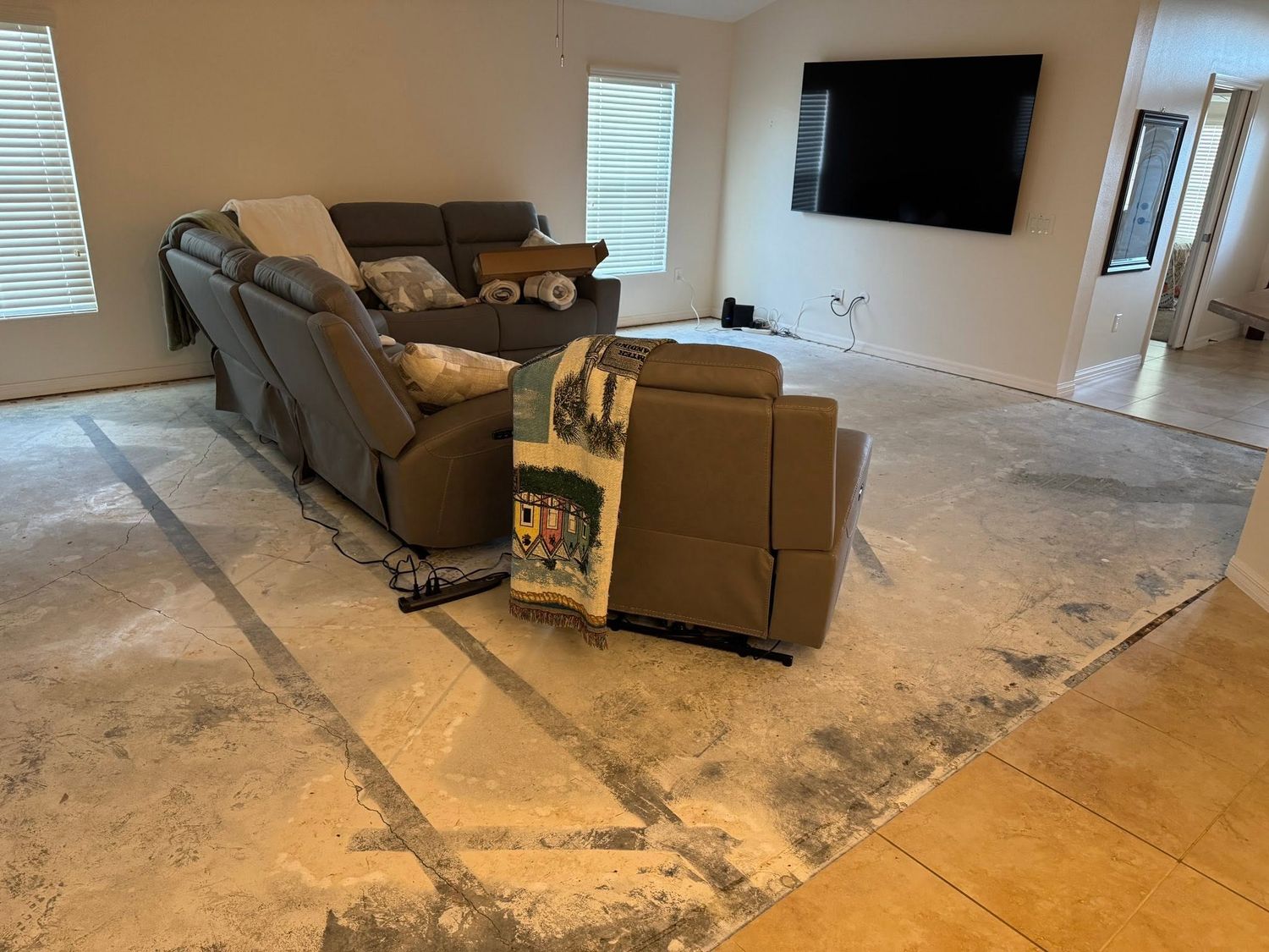 Living room during flooring demolition, with the old floor removed down to bare concrete slab