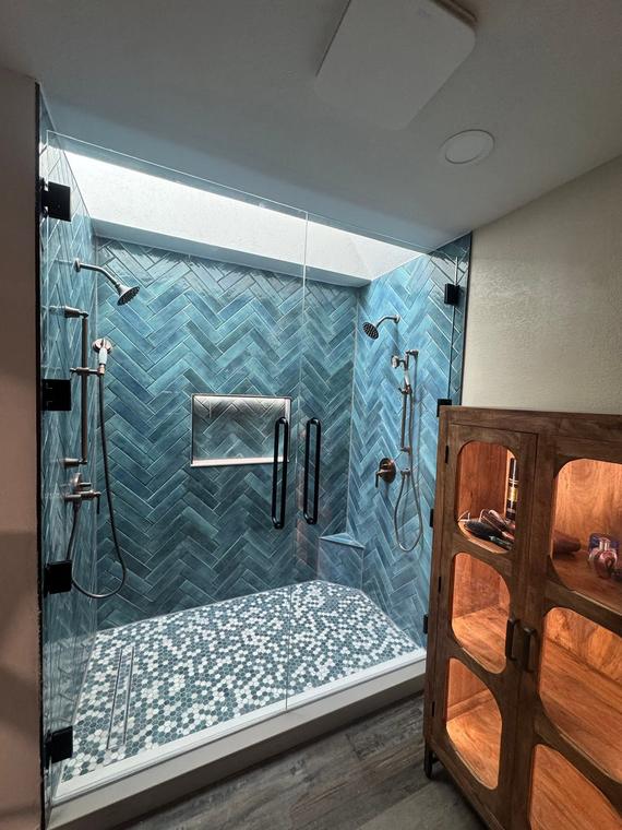 Custom herringbone tile shower with pebble floor and frameless glass