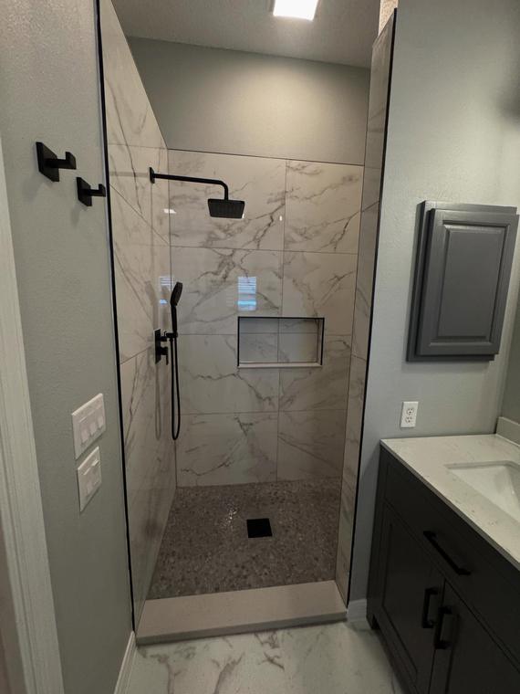 Walk-in shower with full-height porcelain slab and frameless glass