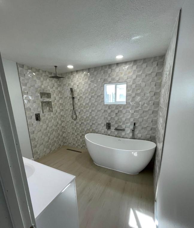 Master bath with textured feature tile, freestanding tub and open walk-in shower