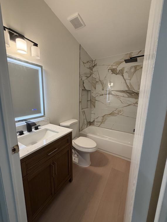 Guest bath with quartz-topped vanity and backlit mirror