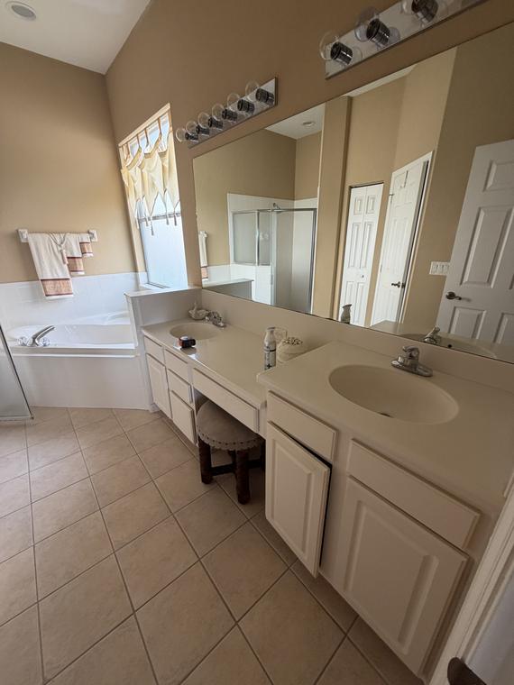 Before — the original master bath, with a double vanity, garden tub and beige tile throughout
