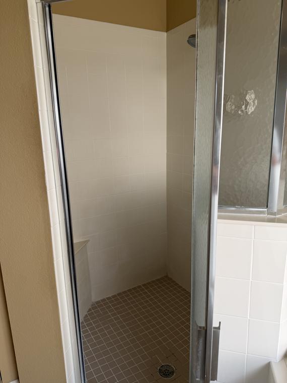 Before — inside the original stall, small-format wall tile and a dated shower head