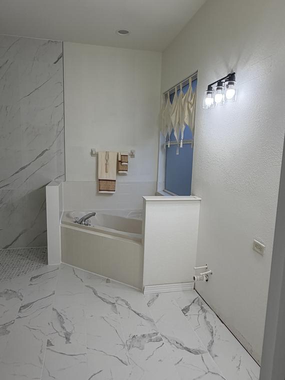 After — the tub wall rebuilt in marble-look porcelain